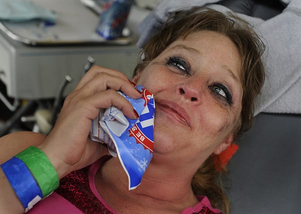Rhonda Gibson tries to crack a smile with an ice pack on her face after she got a tooth pulled and was still feeling some pain. She's from Coeburn, Va. and has no dental insurance. (Michael S. Williamson/The Washington Post)